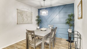 En matplats med ett träbord, stolar, en jordglob, en hängande lampa och krukväxter.
