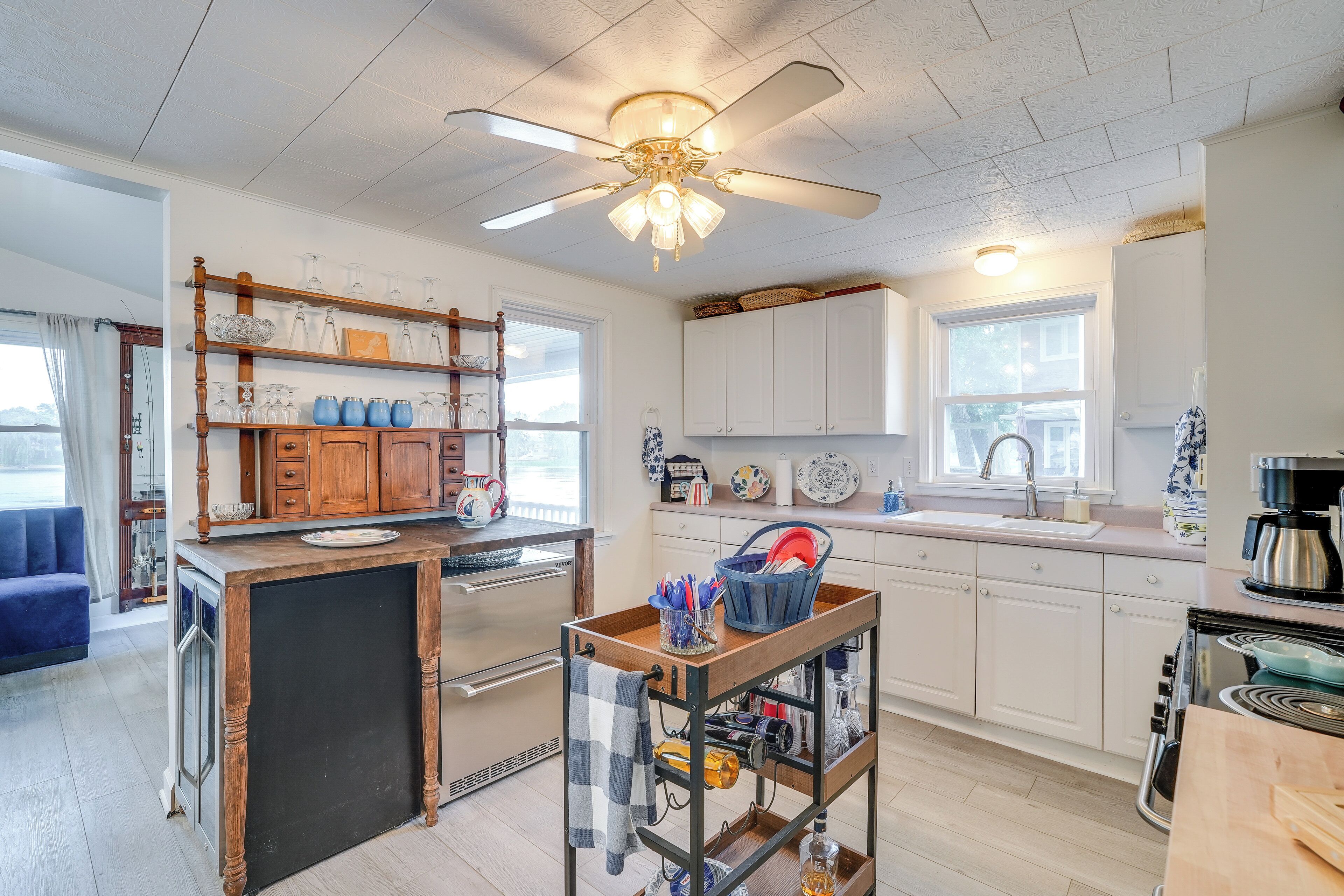 A modern kitchen with white cabinets, a wooden island, and a ceiling fan.