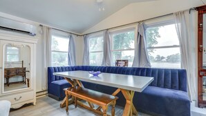 Un área de comedor con un banco tapizado en azul, un banco de madera y una mesa blanca.