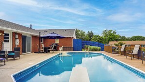 A rectangular swimming pool with a wooden deck, surrounded by a blue fence and outdoor furniture. - Dayton Family Home w/ Game Room: Walk to City Park (Dayton)