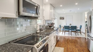 A modern kitchen with stainless steel appliances, a granite countertop, and a dining area with a table and chairs. - Dayton Family Home w/ Game Room: Walk to City Park (Dayton)