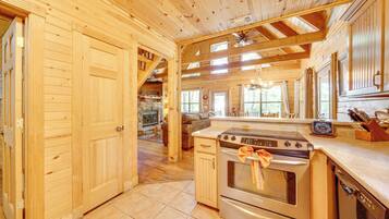 Interior de una cabaña de madera con cocina equipada: estufa, horno y lavavajillas.