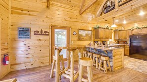 L’intérieur d’un chalet en bois comprend une cuisine, des tabourets en bois, un extincteur et une horloge murale.