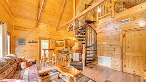 L’intérieur d’un chalet en bois comprend un escalier en colimaçon, un canapé, un coin repas et une cuisine.