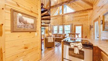 Interior de una cabaña de madera con comedor, cocina y sala de estar.