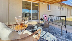 Un patio techado con muebles de mimbre, una hamaca y un tapiz estampado.