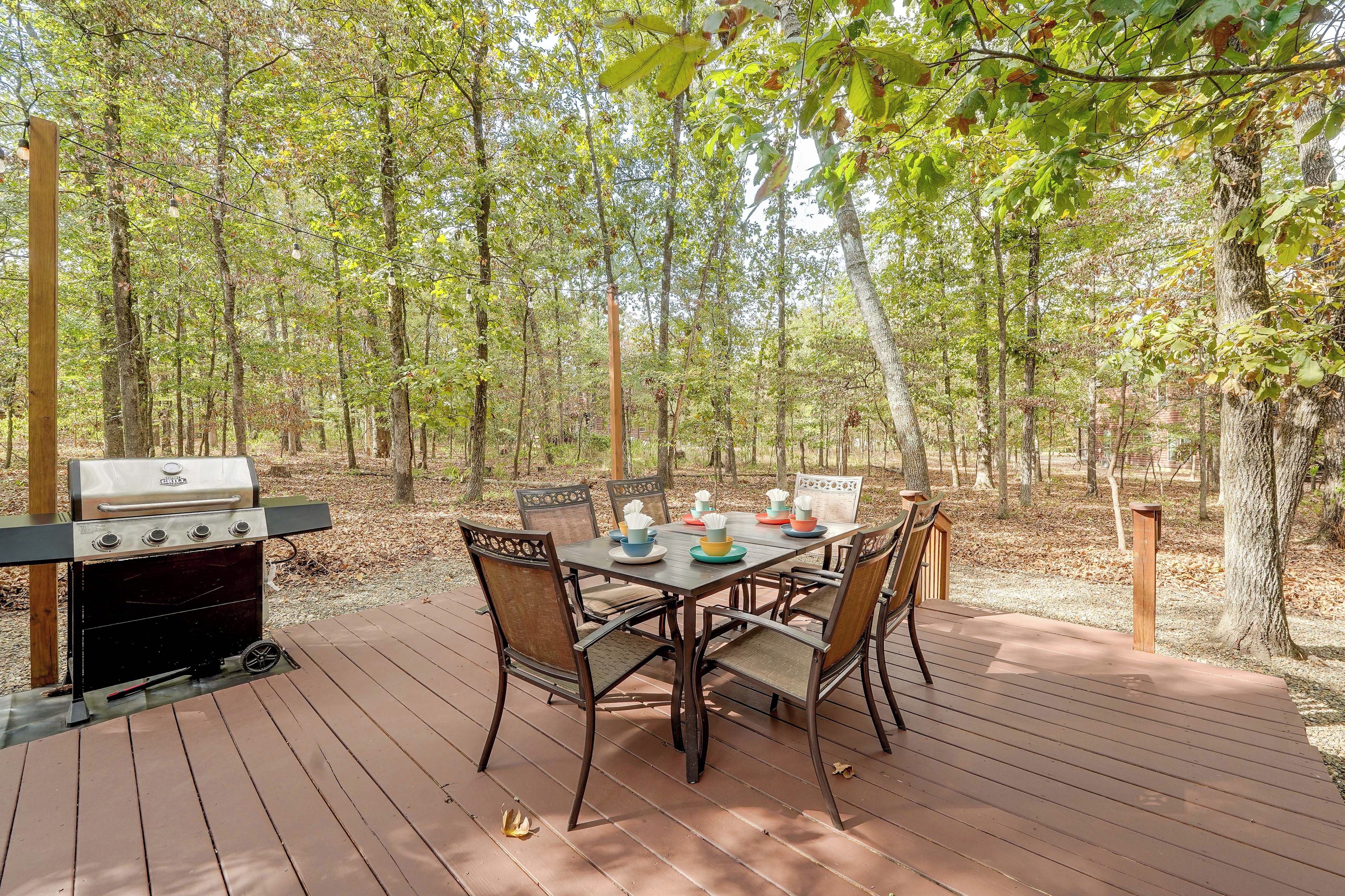 Un espacio de comedor al aire libre con una parrilla, cubierta de madera y sillas.