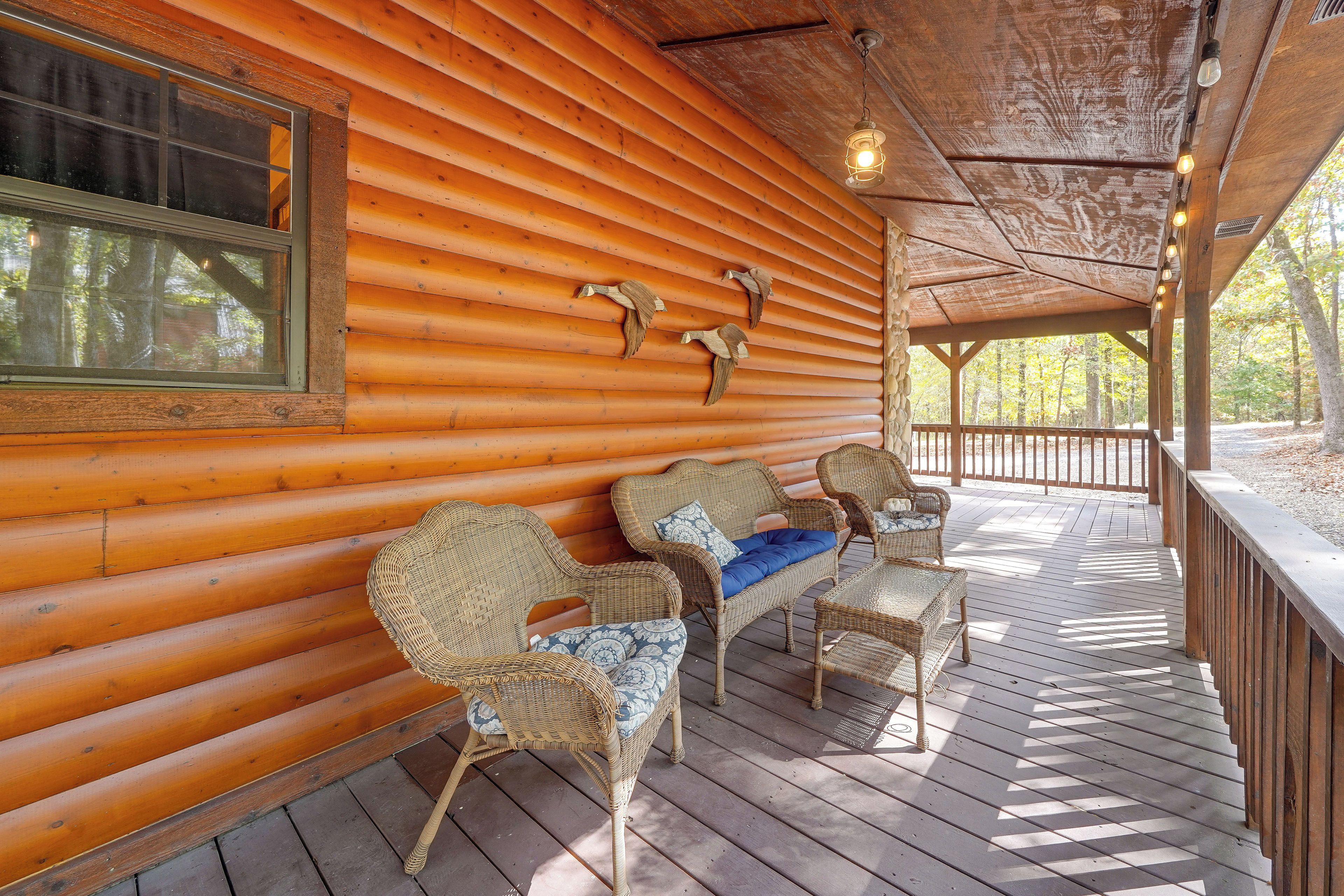 A wooden cabin with a porch featuring wicker furniture and decorative wall mounts.