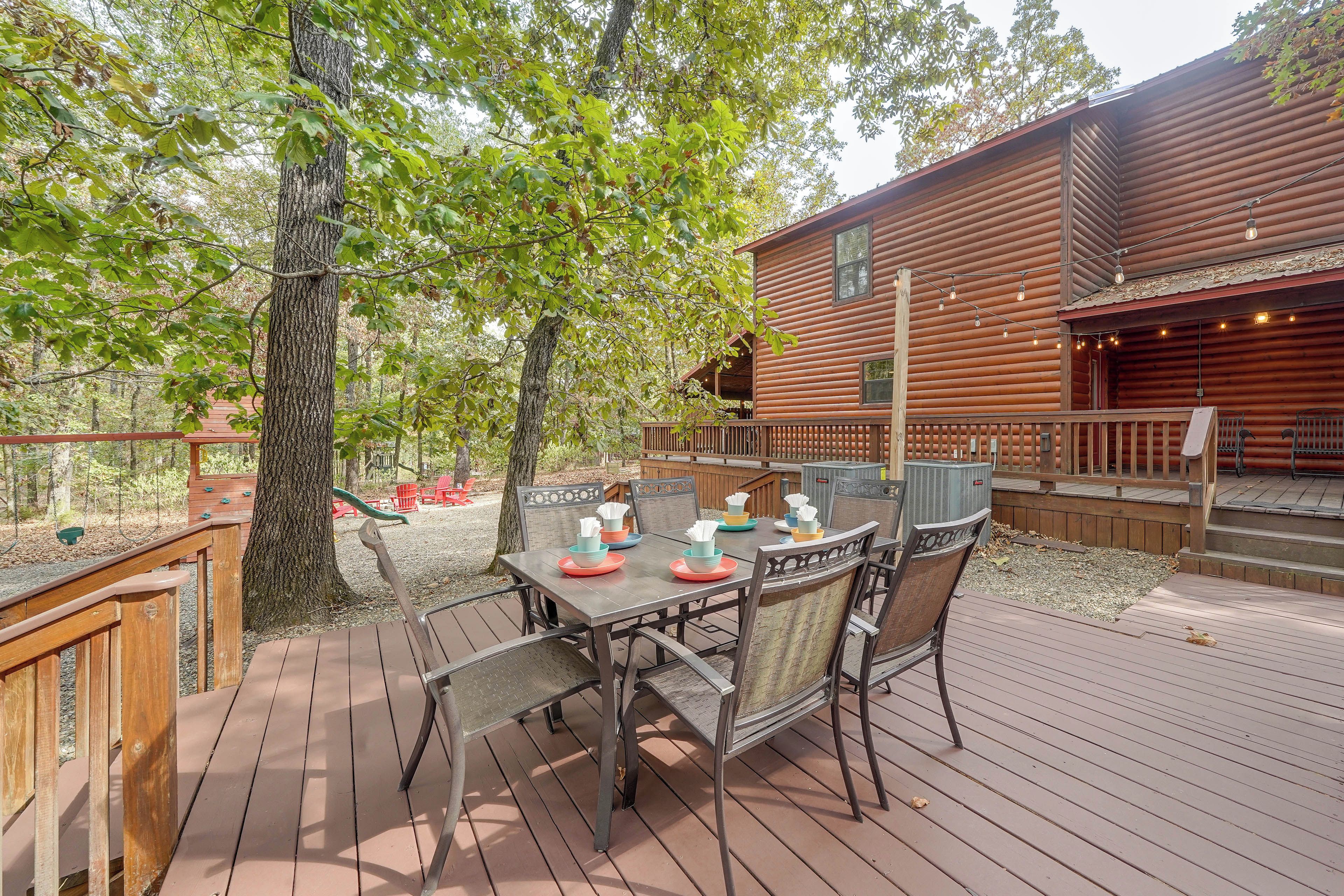 A wooden deck with a table and chairs, surrounded by trees.