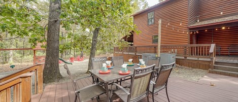 A wooden deck with a table and chairs, surrounded by trees.