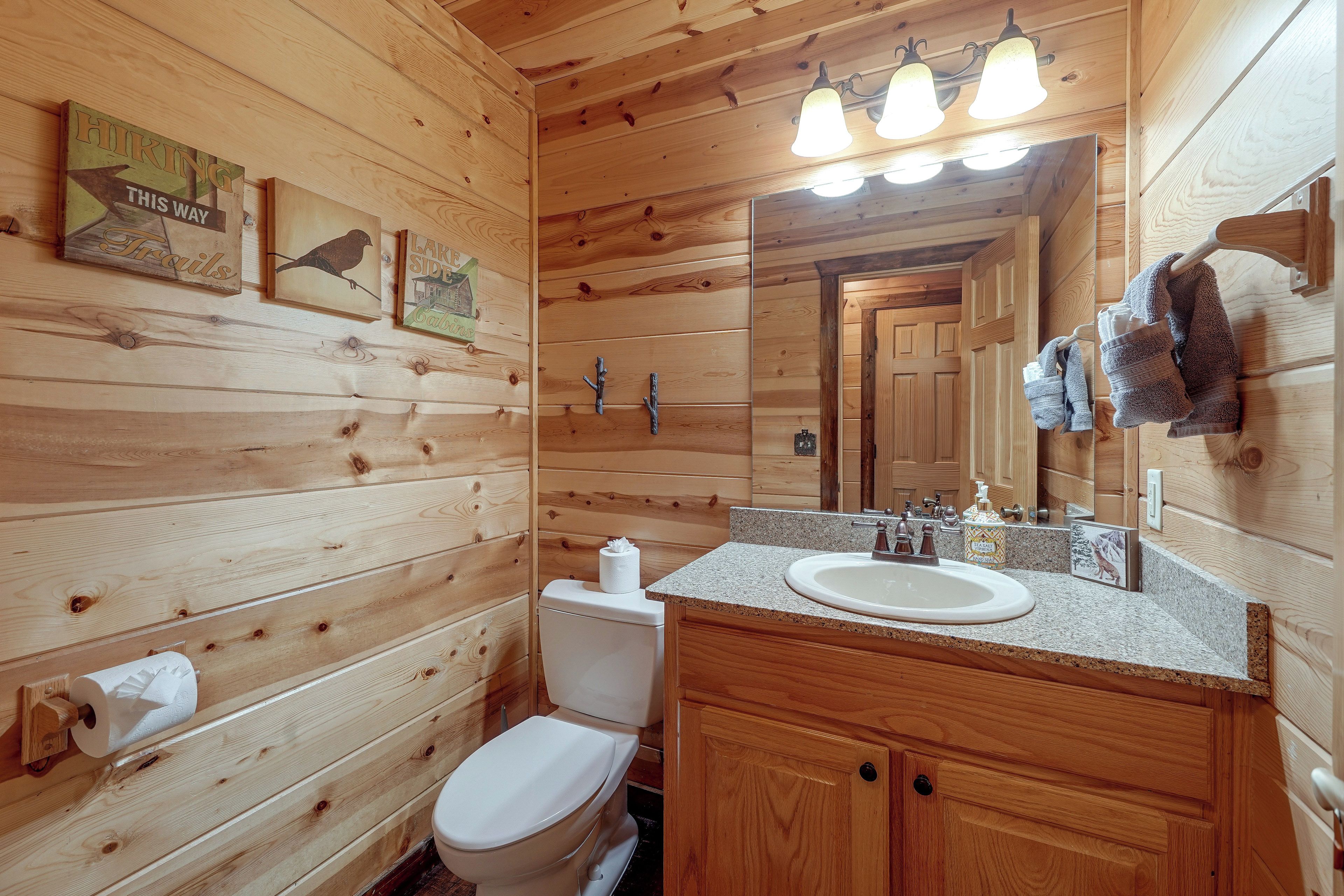 A wooden cabin bathroom with a toilet, sink, and mirror.