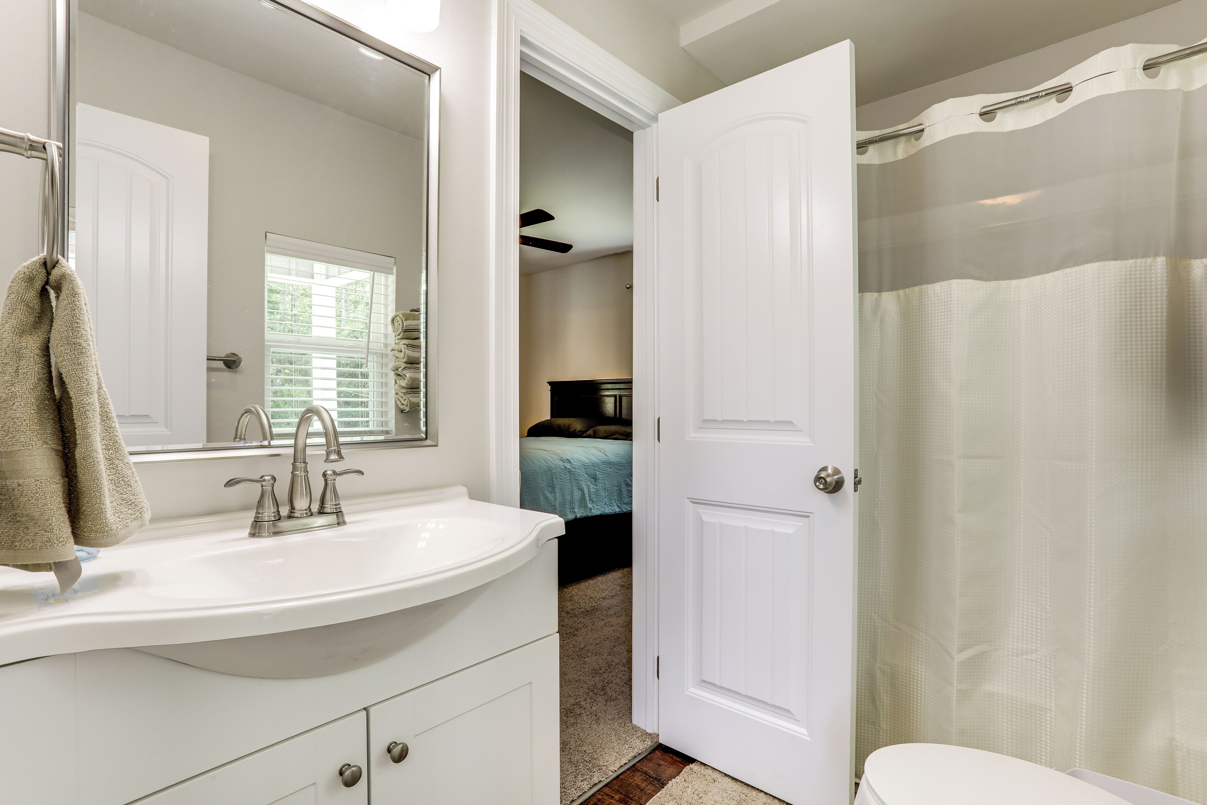 Baño con lavamanos blanco, espejo y cortina de ducha.