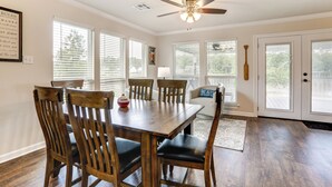 A dining area with a wooden table and chairs, a ceiling fan, and large windows with blinds. - Riverfront Family Retreat w/ Yard in Saint Amant (Saint Amant)