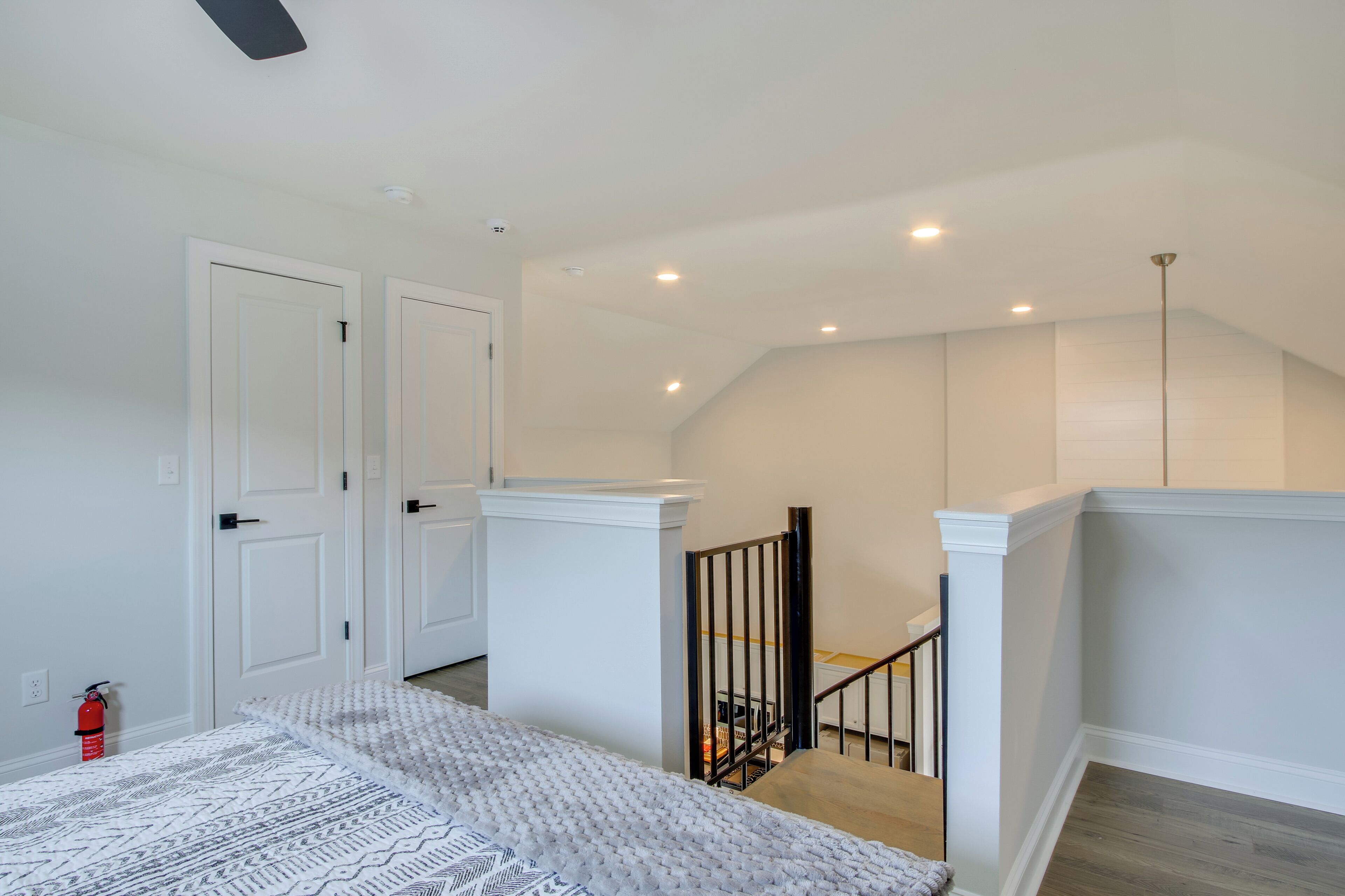A spacious room with a large bed, a staircase, and a door leading to another room.