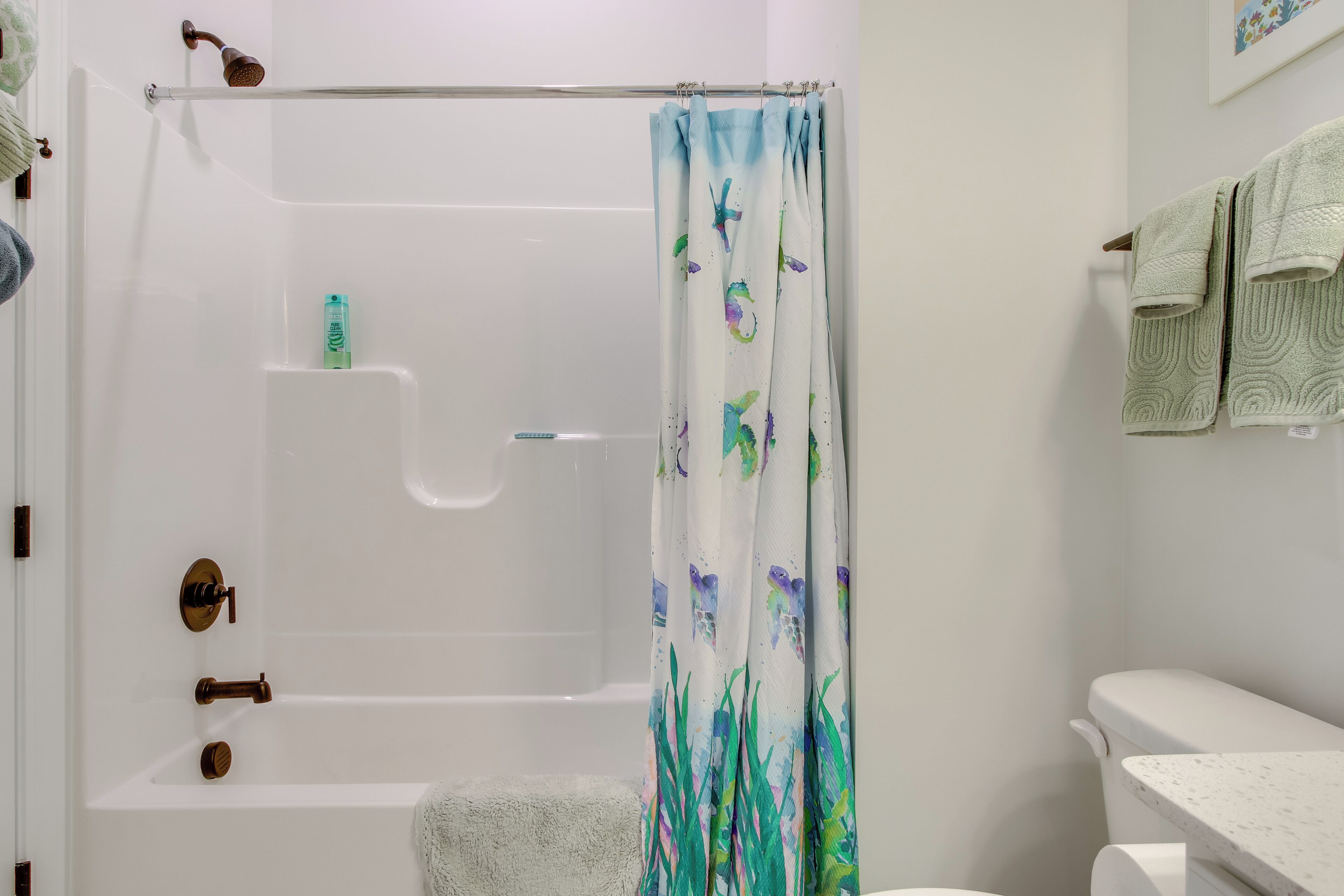 Un baño con bañera, cortina de ducha y toallero.
