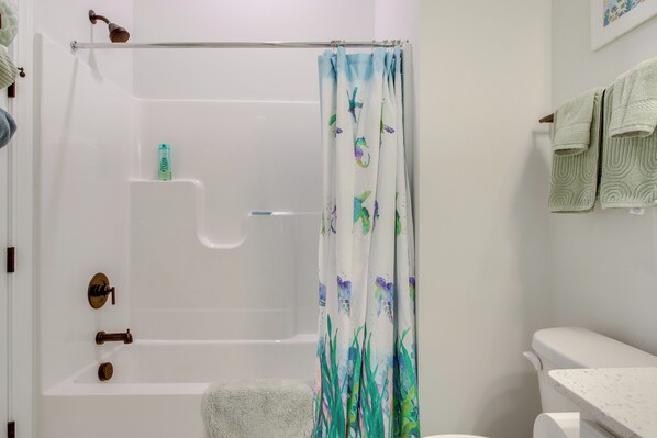 A bathroom with a bathtub, shower curtain, and towel rack.