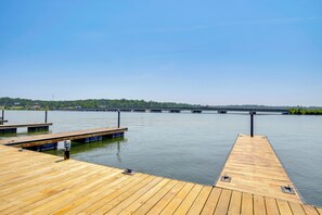 A wooden dock extending into calm water with a clear sky above.