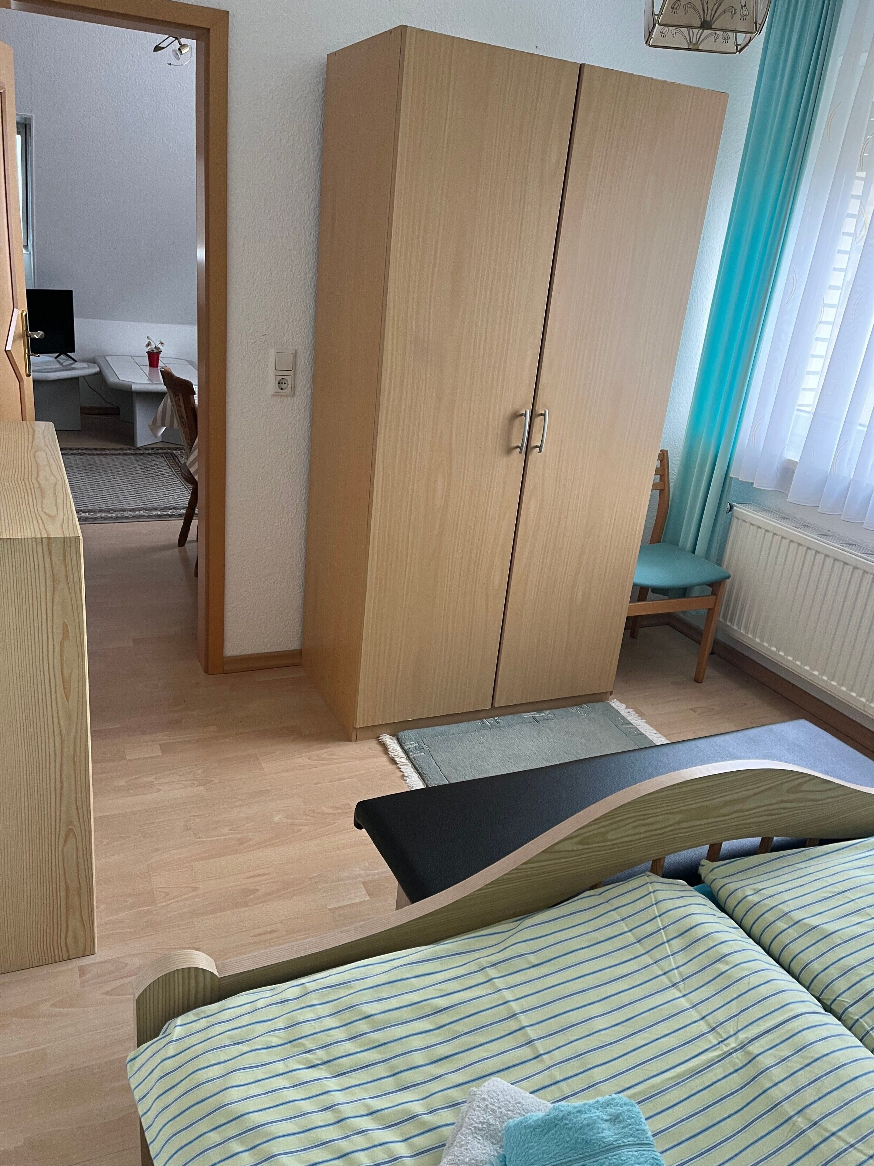 Huoneessa on sänky, vaatekaappi, työpöytä ja tuoli.