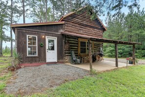 Ein rustikales Holzhaus mit Veranda, einer Tür und einer kleinen Sitzgelegenheit im Freien.