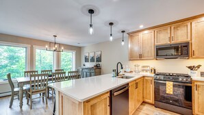 Una cocina moderna con armarios de madera, una isla central, lavavajillas, estufa y microondas.