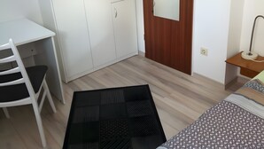 A bedroom with a bed, a desk, a chair, a wardrobe, and a mirror. - Apartment 'Einzelzimmer' with Wi-Fi (Cuxhaven)