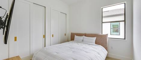 A bedroom with a bed, a ceiling fan, a window, and a door.