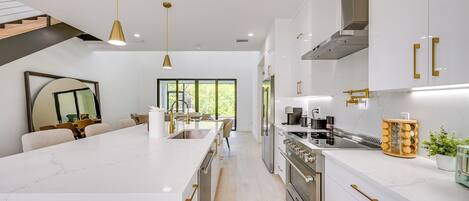 A modern kitchen with white cabinetry, stainless steel appliances, and a large island.
