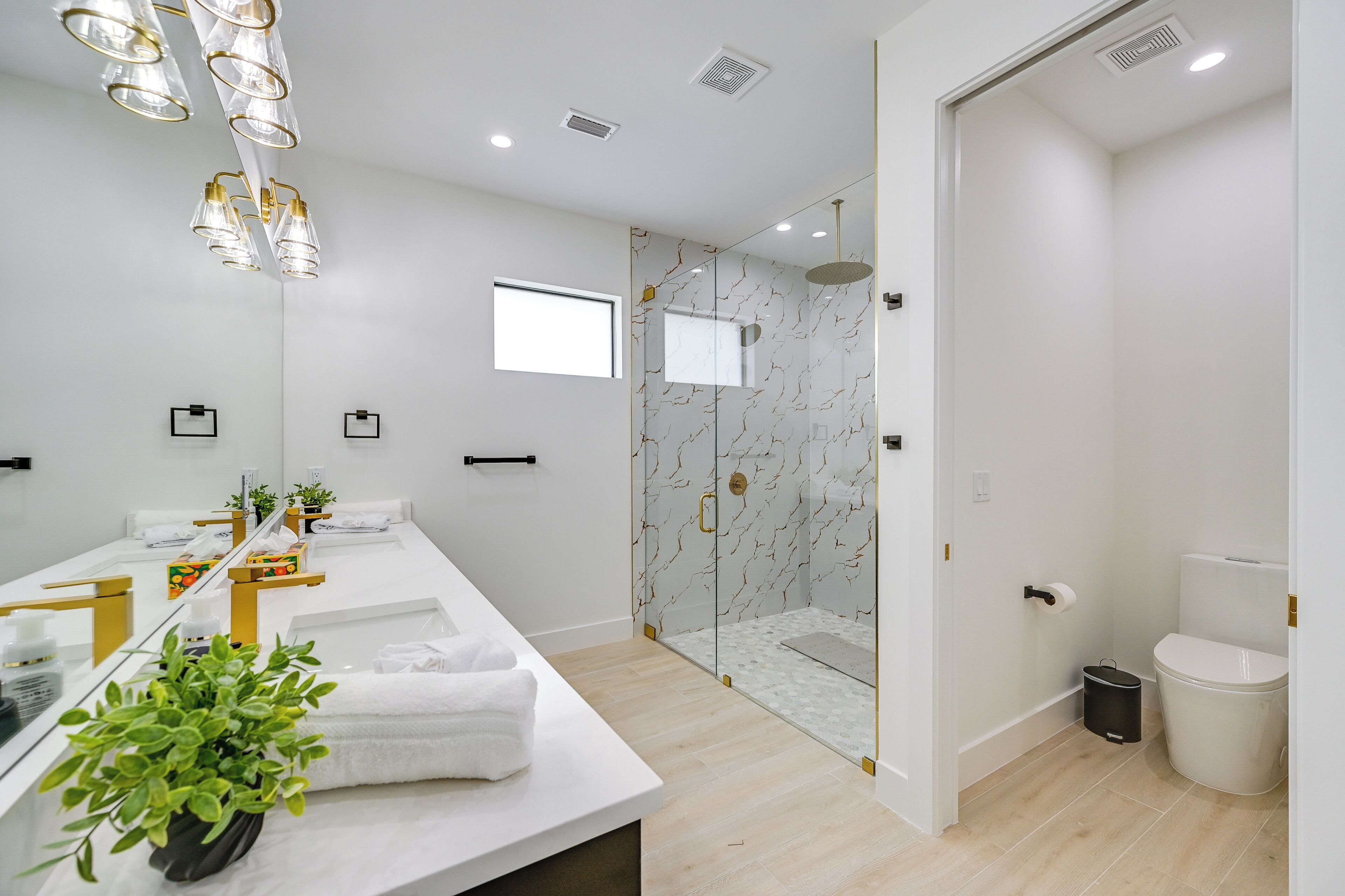 A modern bathroom with a glass-enclosed shower, a large mirror, and a white vanity with towels.