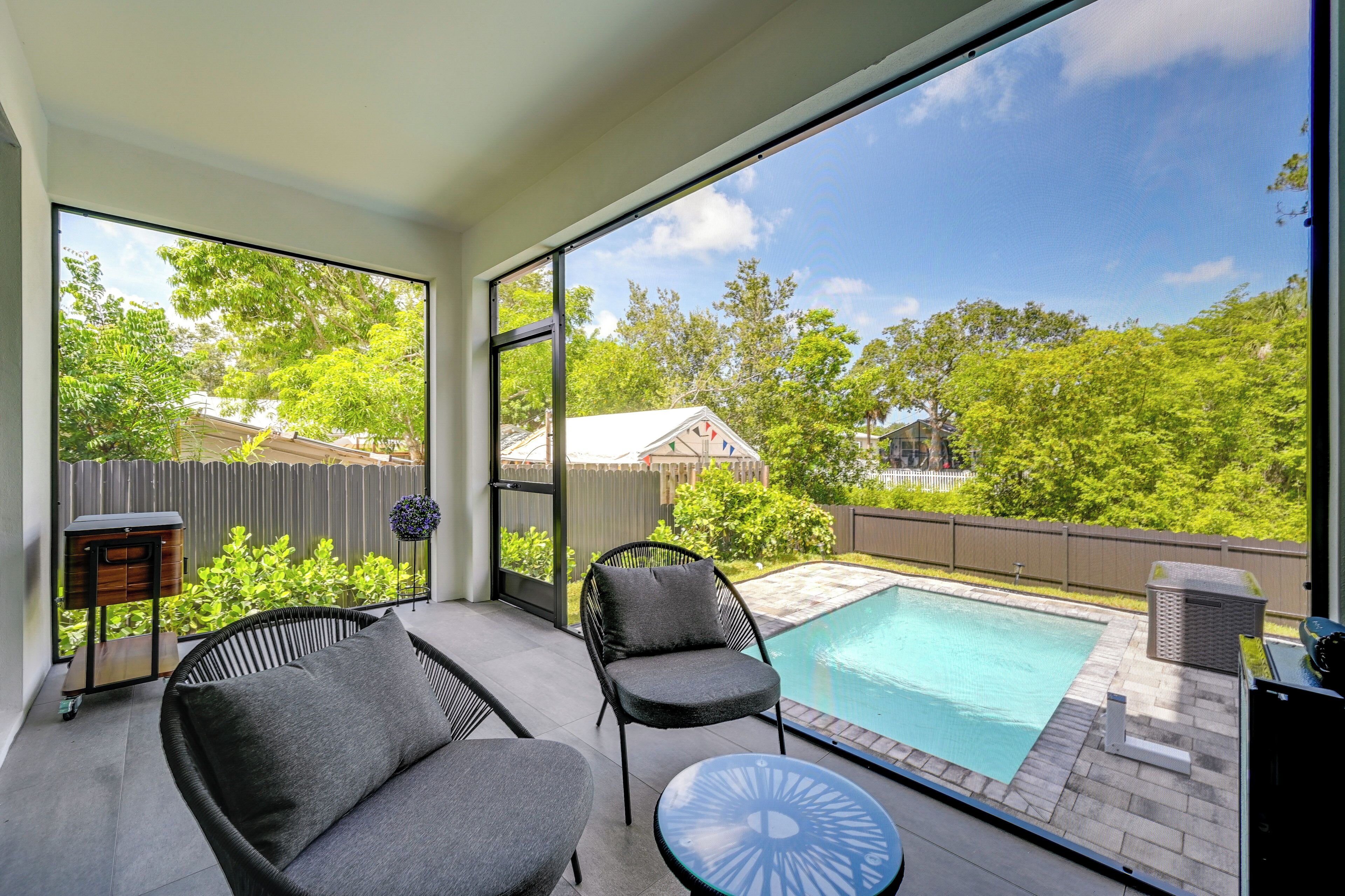 Eine moderne Terrassenanlage im Freien mit Pool, zwei Stühlen und einem Tisch.