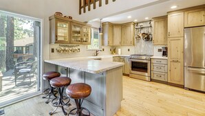 Una cocina moderna con armarios de madera, electrodomésticos de acero inoxidable y una isla grande con taburetes de bar.