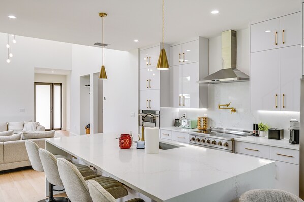 A modern kitchen with white cabinetry, a central island, and gold handles. - 3 Mi to Naples Beach: Luxurious Home w/ Pool! (Naples)