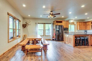 Une cuisine spacieuse avec des meubles en bois, un grand îlot central doté de tabourets, un ventilateur de plafond et une tête de cerf fixée au mur.