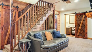 A living room with a leather sofa, a wooden staircase, and a sliding barn door. - Brian Head Cabin < 1 Mi to Resort: Ski + Mtn Bike (Brian Head)
