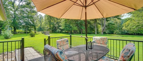 Eine Terrasse mit Gartenmöbeln, einem Tisch und einem großen Sonnenschirm.