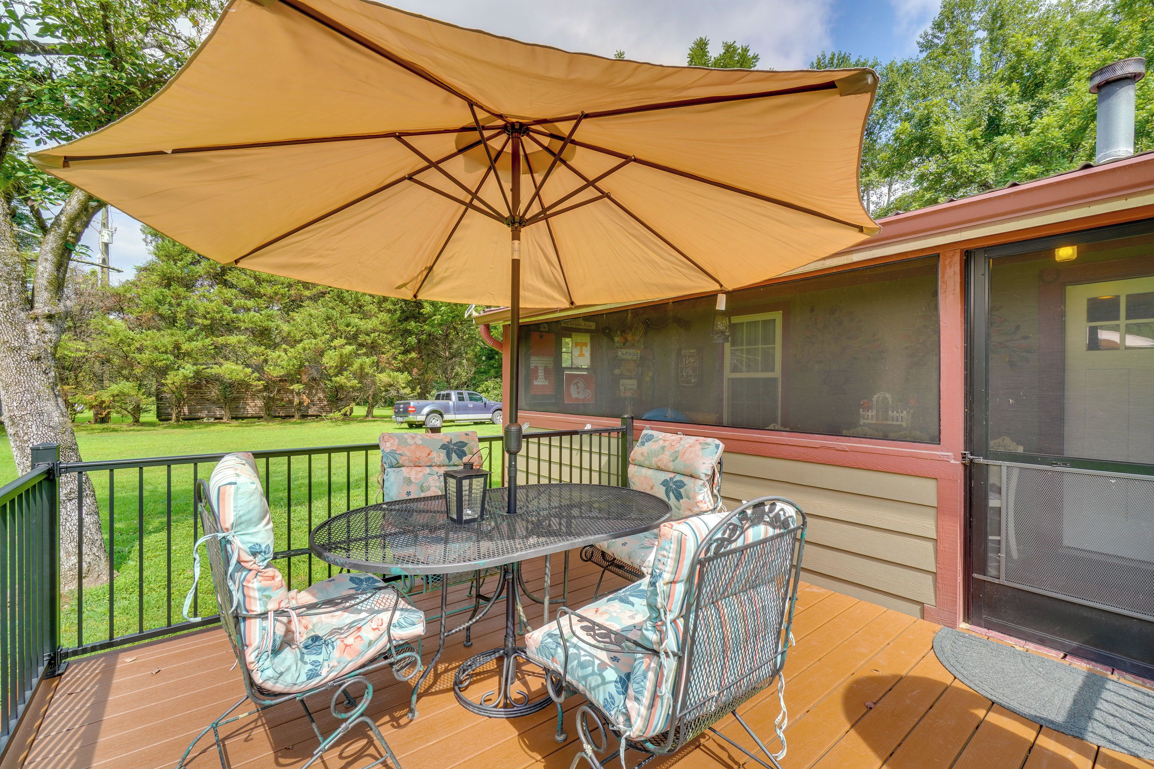 A covered outdoor seating area with a table and chairs, a large umbrella, and a view of the surrounding landscape.