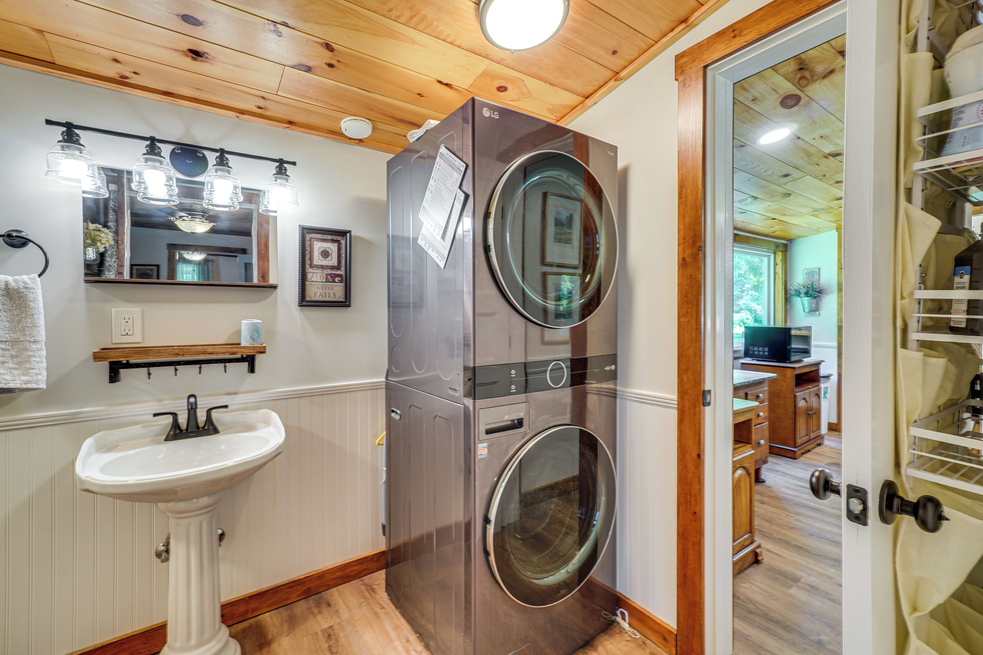 A laundry room with a washing machine, a sink, and a mirror.