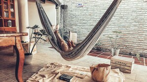 A hammock in a room with a brick wall, a wooden cabinet, and a tiled floor.