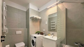 Un baño moderno con lavadora, inodoro, lavabo y ducha.