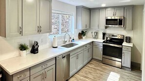 A modern kitchen with grey cabinets, stainless steel appliances, and a window providing natural light. - Astoria 4BR Nr Riverwalk Fishing Coastal Views (Astoria)