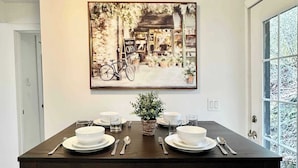 A dining table set with white plates, bowls, and cutlery, with a potted plant in the center. - Astoria 4BR Nr Riverwalk Fishing Coastal Views (Astoria)