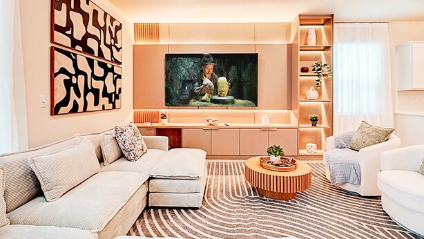 A modern living room with a large flat-screen TV, a sofa, a coffee table, and a patterned rug. - 15807 Luxury 8 Bedroom Family Home With Game Room (Clermont)