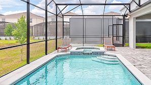 A swimming pool with a glass enclosure, surrounded by a patio area with chairs and a hot tub. - 15807 Luxury 8 Bedroom Family Home With Game Room (Clermont)