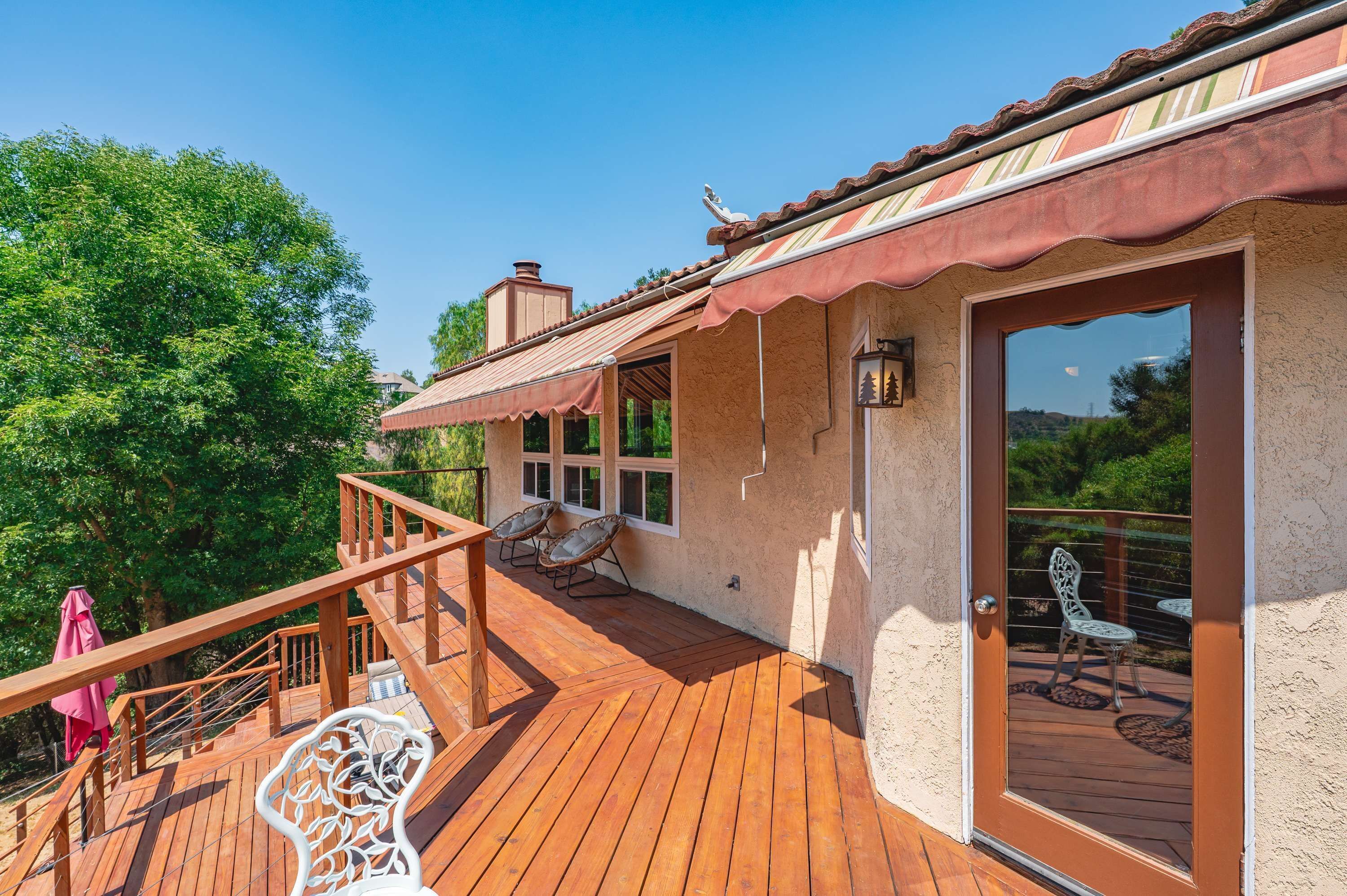A wooden deck with outdoor seating, a staircase, and a door leading to a covered area.