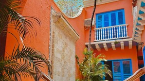 A pool area with a hammock, palm trees, and a building with blue shutters. - Nok Charming Colonial Villa Ctg (Cartagena)