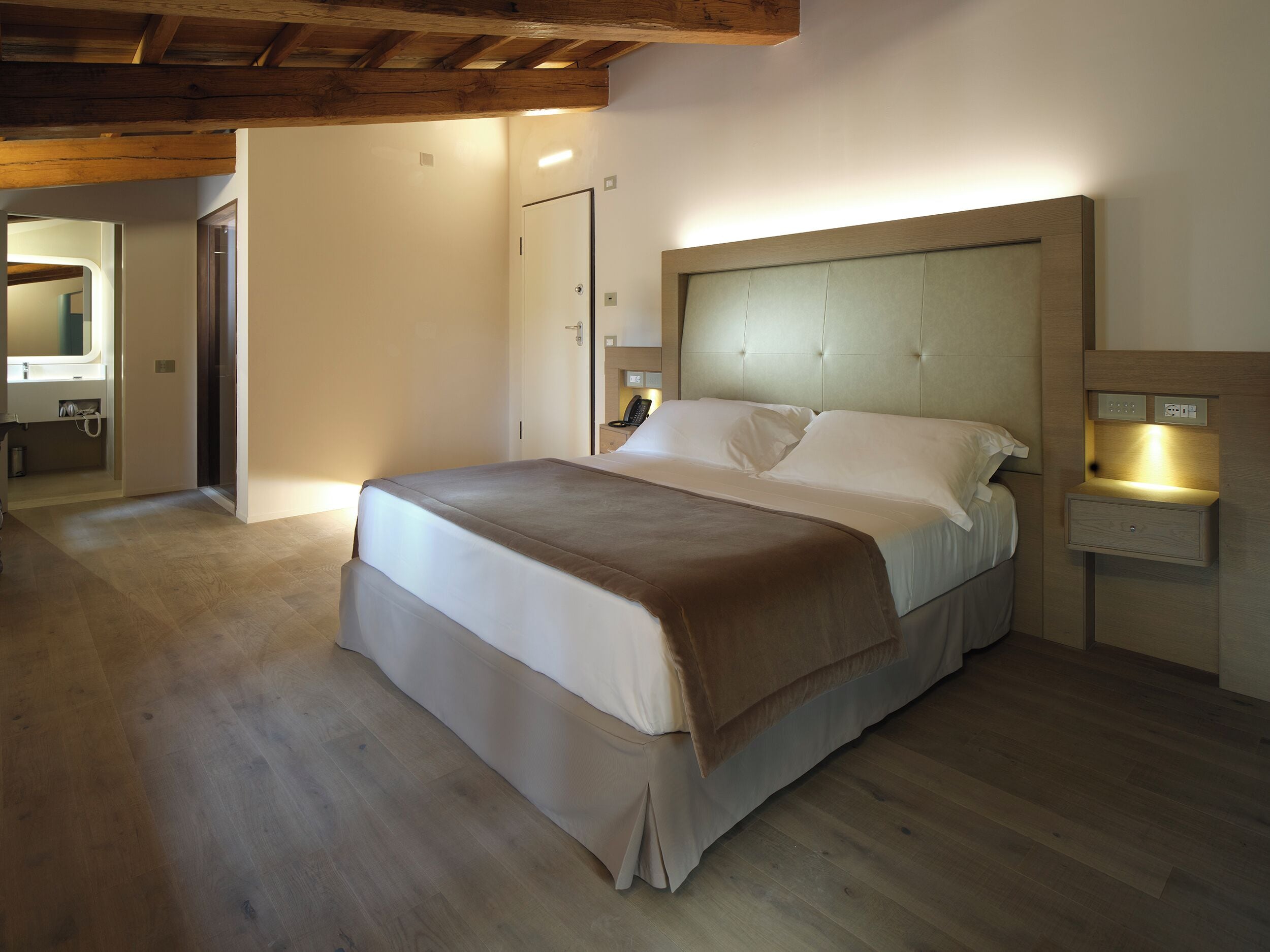 Un dormitorio con una cama grande, una mesita de noche y un techo de madera.