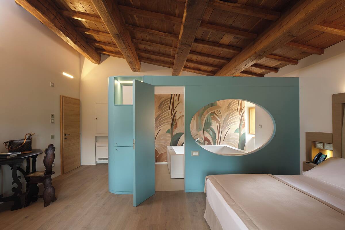 A bedroom with a wooden ceiling, a bed, a desk, and a chair.