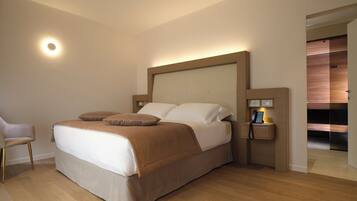 A modern hotel room with a large bed, bedside table, and a chair.