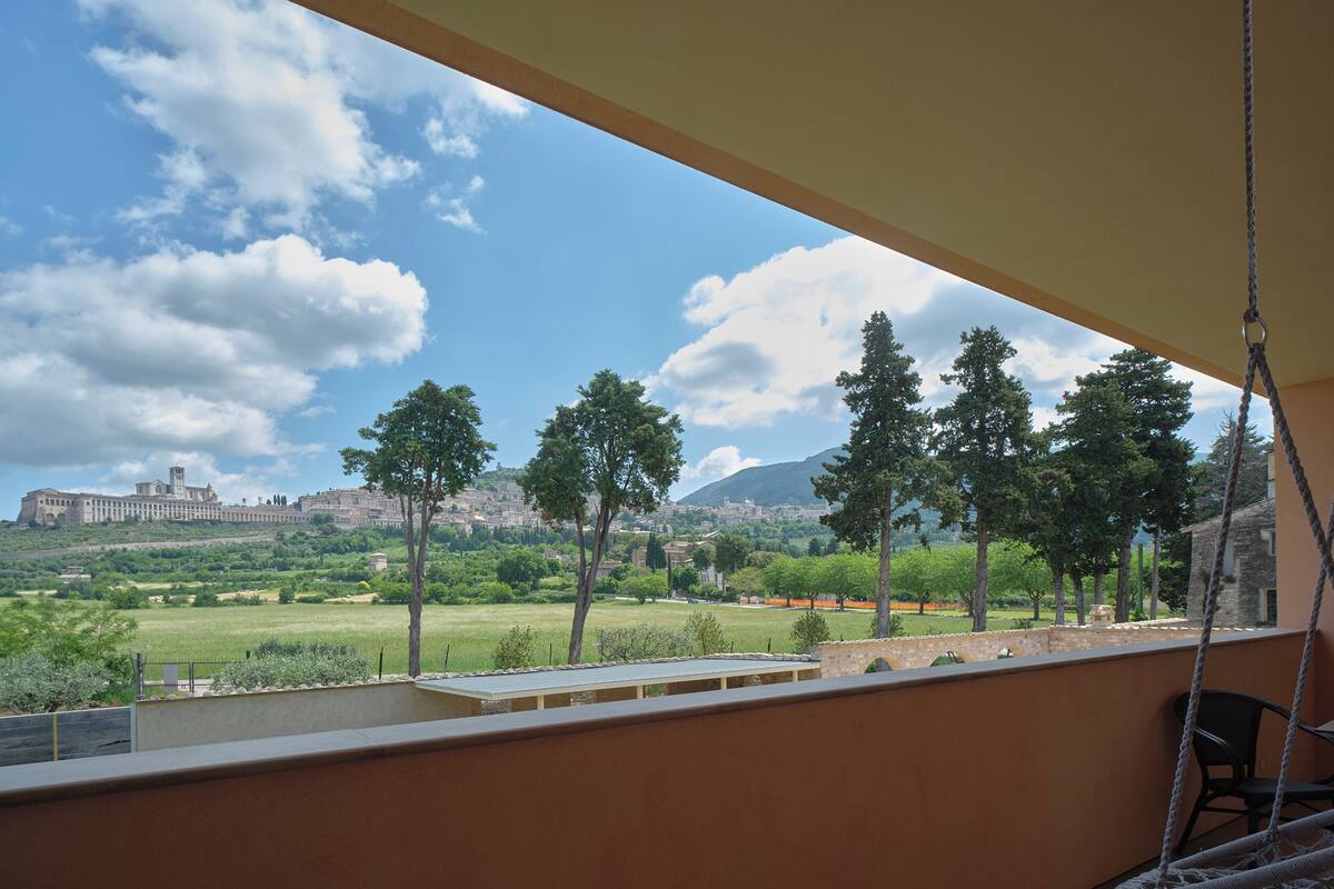 A balcony with a view of a historic building, trees, and a grassy field.
