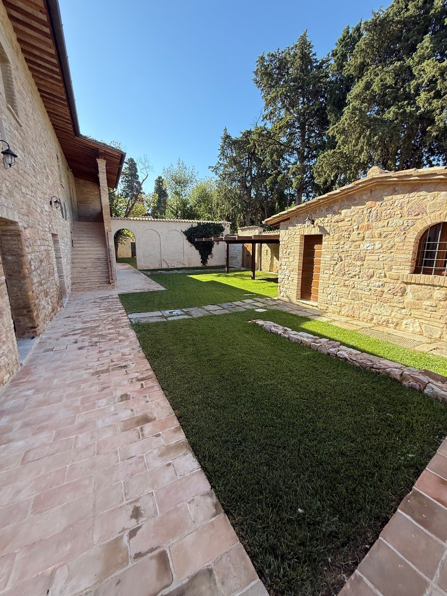 Un patio con un edificio de piedra, un camino empedrado y un césped cuidado.