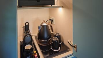 Une petite cuisine équipée d’une machine à café, d’une bouilloire et d’un service à thé.